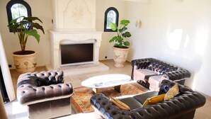 Ein Wohnzimmer mit Kamin, zwei Ledersofas, einem Couchtisch und zwei Blumentöpfen.