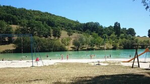 Une plage avec des balançoires et un toboggan, entourée d’arbres et de collines.