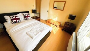 Une chambre d’hôtel comprenant un lit, des tables de chevet, une commode, un miroir et un radiateur.