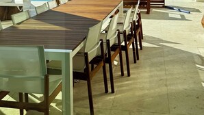 An outdoor terrace with a wooden table and chairs, a white umbrella, and a view of the sea. - Villa Solea - Stunning New Luxury 6-bedroom villa in beautiful Playa Hermosa (Playa Hermosa)