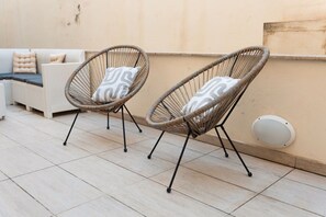 Two wicker chairs with cushions on a tiled patio area. - Ortigia Collection / Suite No.1 / Terrace (Swieqi)