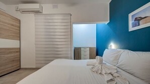 A hotel room with a bed, a wardrobe, a bedside table, and a wall-mounted air conditioner. - Ortigia Collection / Suite No.1 / Terrace (Swieqi)