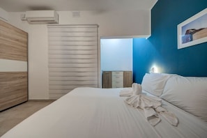 A hotel room with a bed, a wardrobe, a bedside table, and a wall-mounted air conditioner. - Ortigia Collection / Suite No.1 / Terrace (Swieqi)