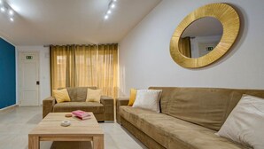 A living room with a sofa, a coffee table, and a round mirror on the wall. - Ortigia Collection / Suite No.1 / Terrace (Swieqi)