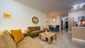A living room with a sofa, coffee table, and dining area with chairs. - Ortigia Collection / Suite No.4 / Terrace (Swieqi)