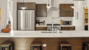 Een moderne keuken met roestvrijstalen apparatuur, houten kastjes en hanglampen.
