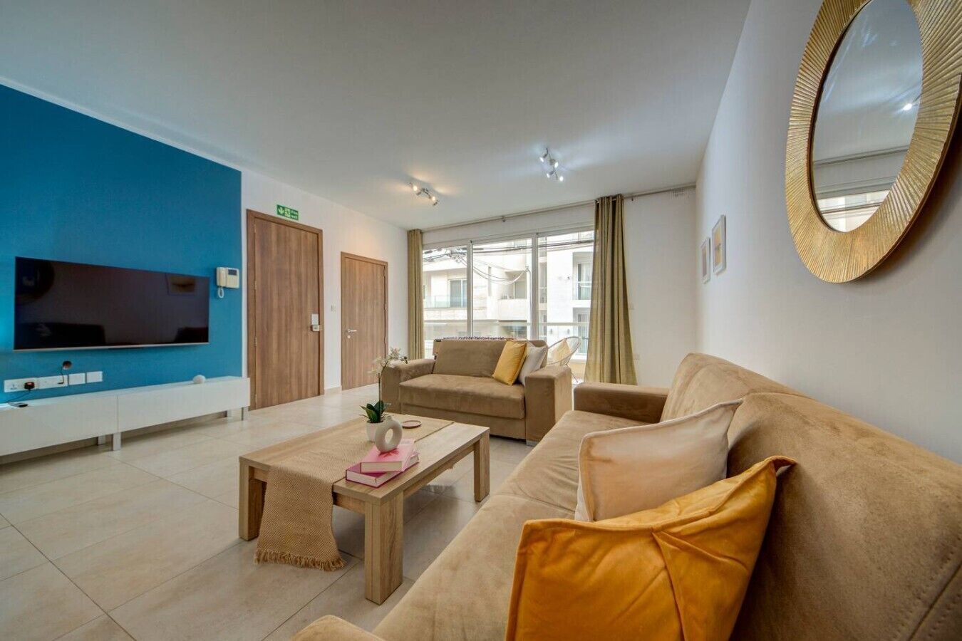 A modern living room with a TV, sofas, a coffee table, and a large window.