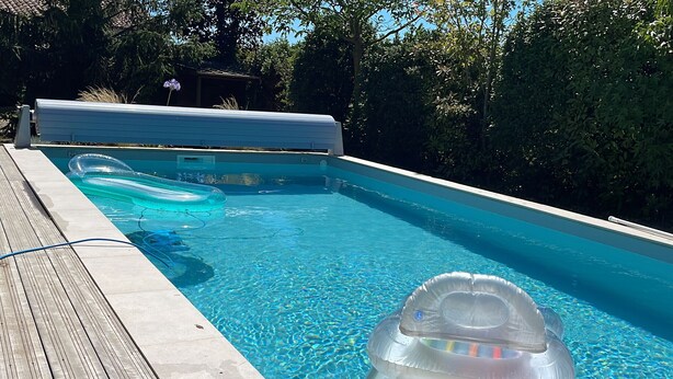 Uma piscina com deck de madeira e uma banheira de hidromassagem.