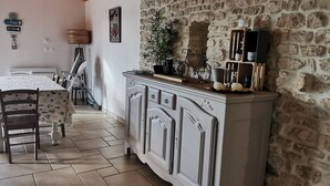 Uma área de refeições com mesa, cadeiras, um armário e uma parede de pedra.
