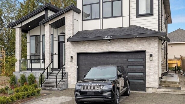 A modern two-story house with a garage, a driveway, and a black Range Rover parked in front.
