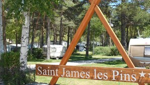 Une enseigne en bois portant l’inscription « Saint-James-les-Pins » et un symbole en forme d’étoile.