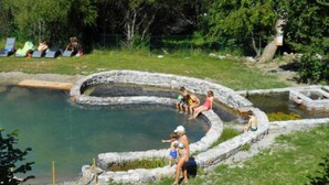 Une source d'eau chaude naturelle dotée de sièges en pierre et d'une terrasse en bois.