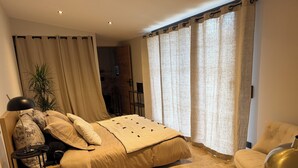 Un dormitorio con cama, escritorio, silla y una planta en maceta.