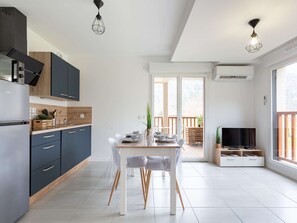 Une cuisine moderne avec des meubles de couleur sombre, un plan de travail en bois et un coin repas comprenant une table et des chaises.