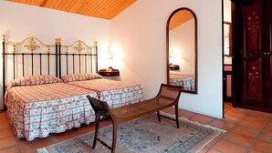 Een slaapkamer met twee bedden, een stoel, een grote spiegel en een kledingkast.