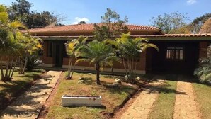 Una casa con techo de tejas, rodeada por un jardín con palmeras y un sendero de piedra.