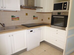A kitchen with white cabinets, a microwave, an oven, and a dishwasher. - Maison Marius—pets allowed—1,600 m² fenced-in garden—heated pool (Le Buisson-de-Cadouin)