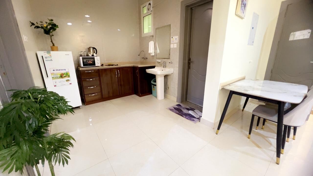 A modern kitchen with a refrigerator, microwave, sink, and wooden cabinets.