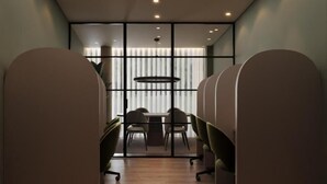 Un salón de conferencias con una larga mesa, sillas y un separador de vidrio.