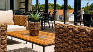 Un área de estar al aire libre con mobiliario de mimbre, una mesa de madera y un gran paraguas.