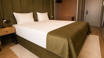 Une chambre d’hôtel bien rangée, avec un lit, une table de chevet, une lampe, une armoire et une porte.