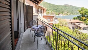 Ein Balkon mit Tisch und Stühlen mit Blick auf einen See und Hügel.
