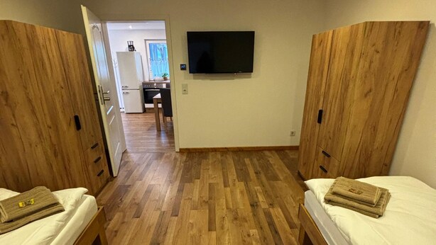 Ein Zimmer mit zwei Holzbett, einem flachbildfernseher an der Wand und einem Holzschrank.