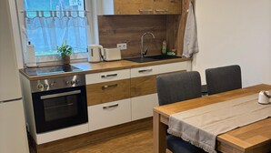 Eine moderne Küche mit Holzschränken, einem eingebauten Ofen und einem Essbereich mit Holztisch und Stühlen.