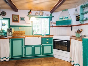 A kitchen with green cabinets, a white stove, and a window with a view of greenery. - 6 Person Holiday Home in Glesborg (Glesborg)