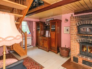 A cozy living room with a fireplace, wooden furniture, and a staircase.