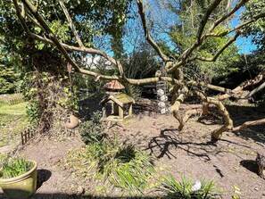 Un jardín con un comedero para pájaros, un bebedero colgante y una planta en maceta.