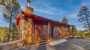 A rustic cabin with a stone chimney, wooden logs, and a metal roof. - Salty Pines - Scenic Log Cabin w/ Hot Tub, Sierra Blanca Views & Pet-Friendly (Ruidoso)