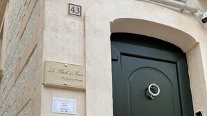Une porte verte avec une poignée en forme d’anneau argenté et un trou de serrure, une plaque portant l’inscription « Lo Perla d’Italia, maison de vacances », et le numéro « 43 » sur le mur.