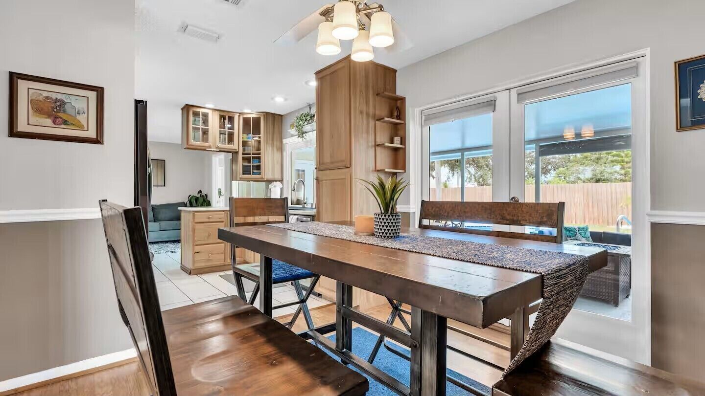 A modern kitchen with wooden cabinets, a dining table, and a large window.