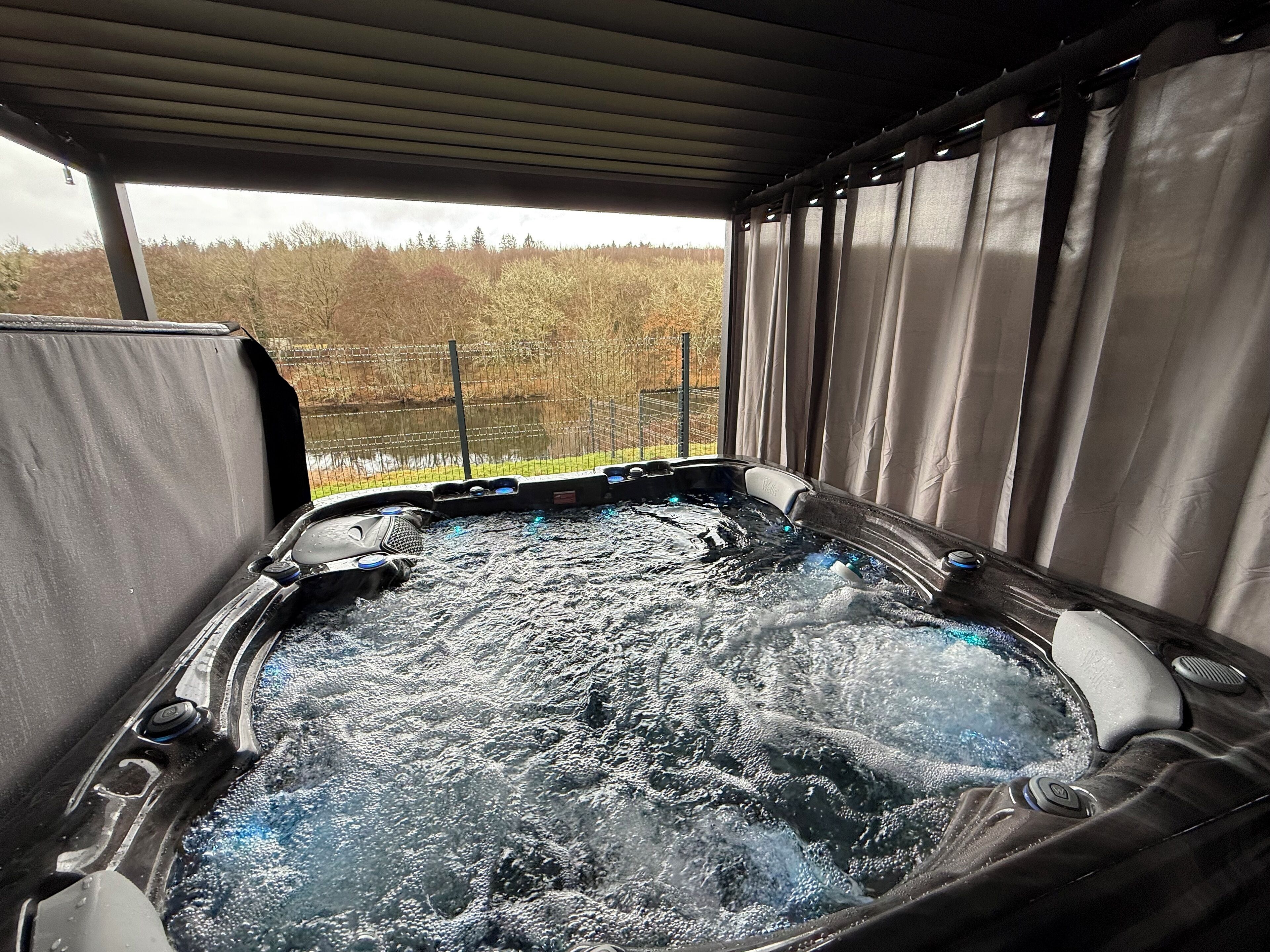 A hot tub with a view of a forested area through a screened enclosure.