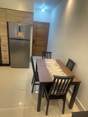 Une cuisine moderne dotée d’un réfrigérateur en acier inoxydable, de meubles de rangement en bois et d’une table à manger avec des chaises.