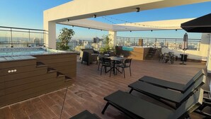 En takterrass med pool, utomhusmöbler och utsikt över staden.