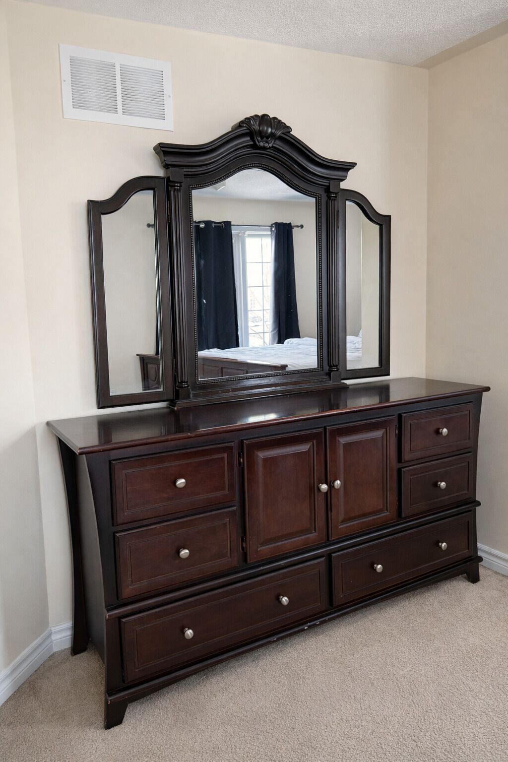 A dark wooden dresser with six drawers and a large mirror above it.