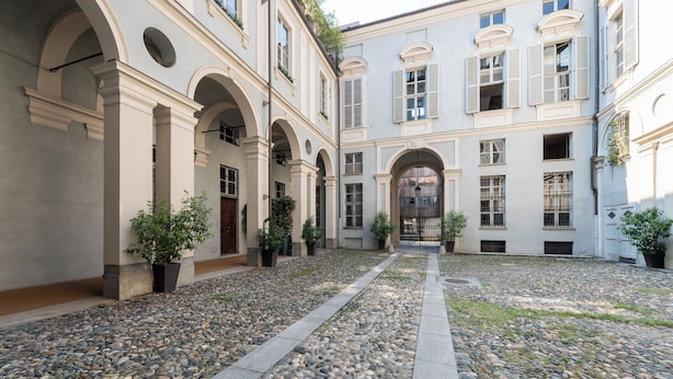 Ein Innenhof mit Kopfsteinpflasterweg, Bögen und Blumentöpfen.