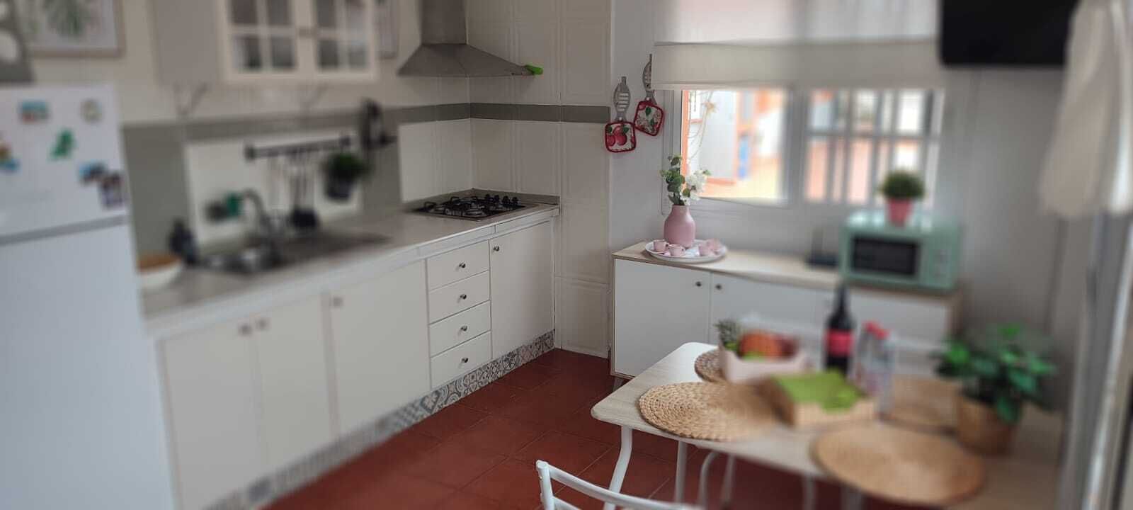 A compact kitchen with white cabinets, a gas stove, and a small dining area with a table and chairs.