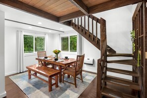 A dining area with a wooden table, chairs, and a staircase. - Family-Friendly Cabin Retreat w/ Private Hot Tub (Mason County)