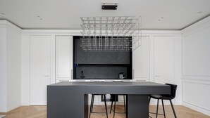 A modern kitchen with a large island, black countertops, and a unique wire shelf above the stove. - Luxury apartment in Old Town + Parking heart of Vilnius (Vilnius)