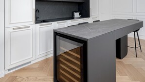 A modern kitchen with white cabinetry, a dark countertop, and a unique hanging light fixture. - Luxury apartment in Old Town + Parking heart of Vilnius (Vilnius)