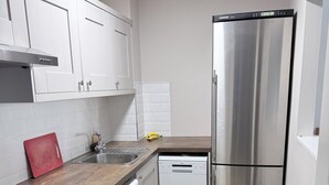 A modern kitchen with white cabinets, a stainless steel refrigerator, a dishwasher, and a washing machine. - Spacious Apartment on a quiet street 1 min from Smithfield Square. (Dublin 7)