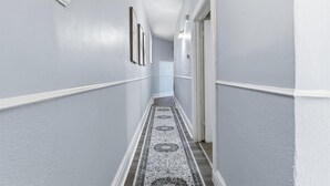 Un couloir aux murs de couleur gris clair, aux moulures blanches et au tapis à motifs.