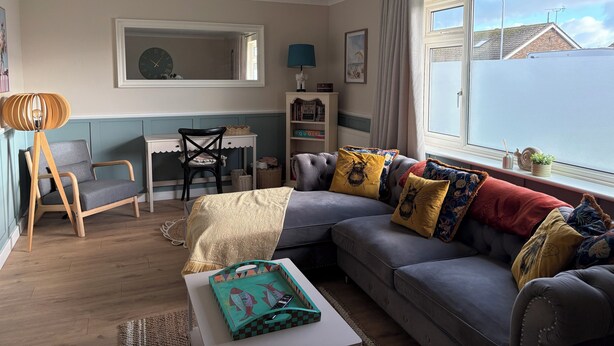Una sala de estar acogedora con un sofá gris, una mesa de centro de madera y un escritorio con una silla.