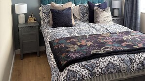 Un dormitorio con cama, mesitas de noche y una ventana con cortinas.