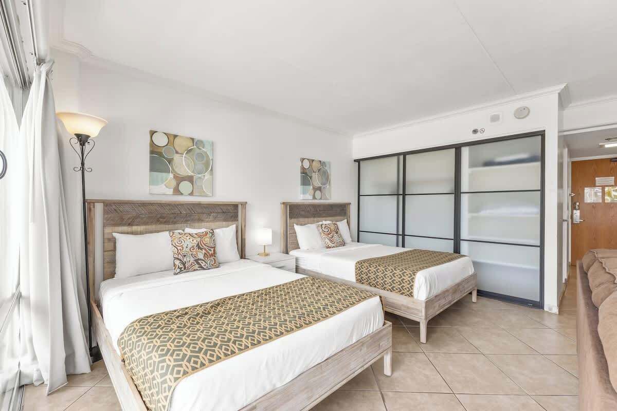 A hotel room with two beds, a large sliding glass door, and a modern design.