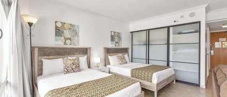 A hotel room with two beds, a large sliding glass door, and a modern design.
