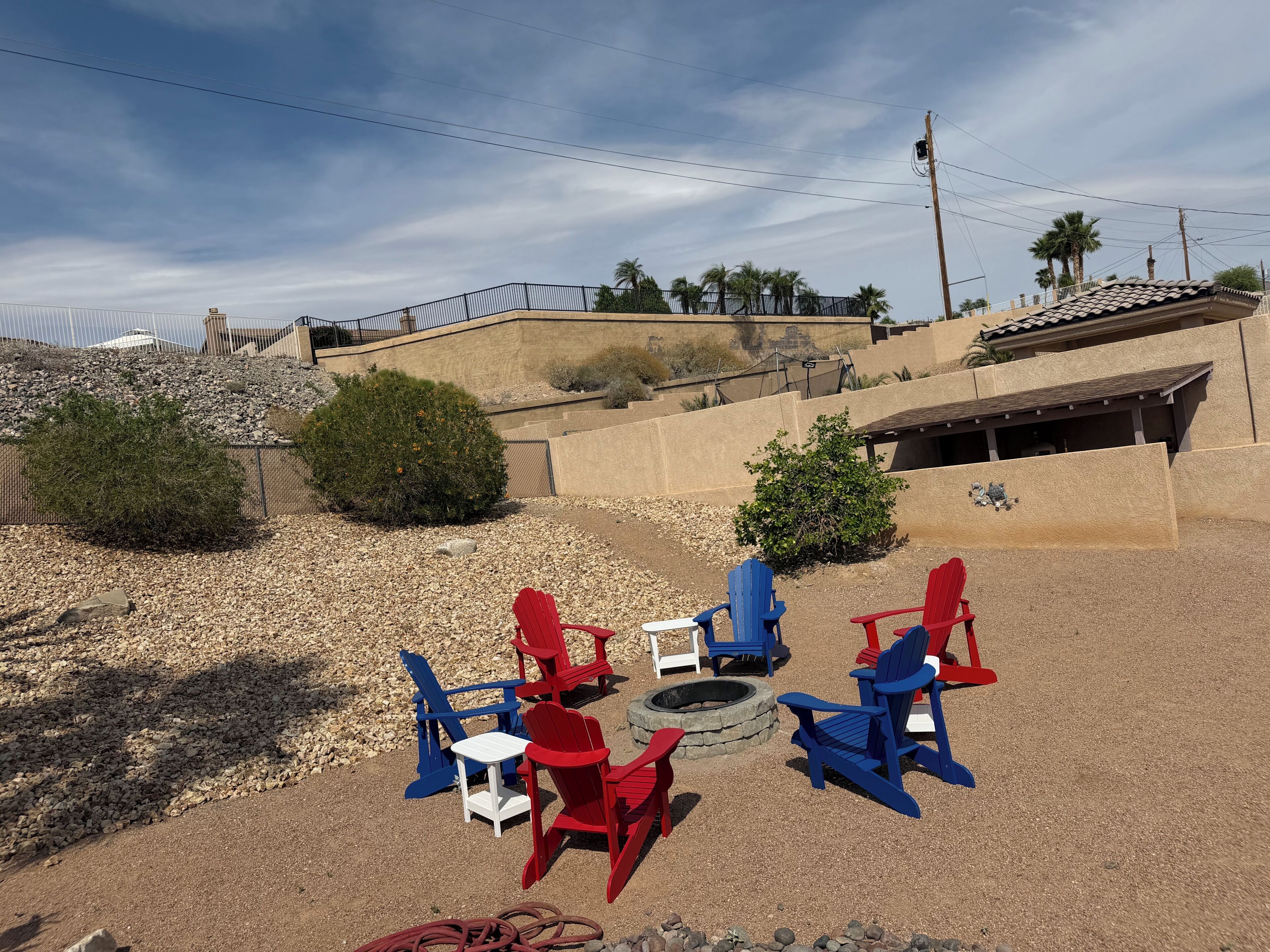 A patio area with Adirondack chairs, a small table, and a fire pit.